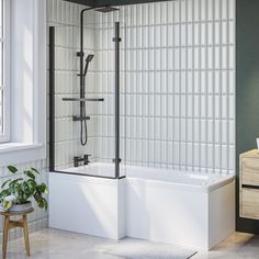 a bath tub sitting next to a window with a plant on the floor in front of it