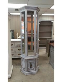 an old china cabinet in the middle of a room with other furniture and cabinets behind it