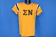 Chest 17 in.Length 23 in. Content: Feels like a cotton blendTag Brand: No tagThis yellow vintage t-shirt has a design for the college fraternity Sigma Nu. The jersey has black and white stripes in rings around the sleeves and neck. The back of the t-shirt has the jersey number '0'.This shirt is an Adult Small.   Jersey-53077 Retro T-shirt With Letter Print For College, Casual Yellow T-shirt With Team Name, Fitted Pre-shrunk College T-shirt, Fitted Pre-shrunk T-shirt For College, Pre-shrunk Collegiate T-shirt For Summer, Fitted Letter Print T-shirt For Game Day, Collegiate Pre-shrunk T-shirt For Summer, Collegiate Summer T-shirt, Collegiate Yellow Tops With Letter Print