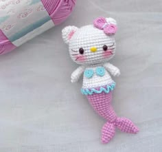 a crocheted hello kitty mermaid doll next to a ball of yarn and a skein of yarn