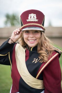 a woman wearing a maroon and black uniform is posing for a photo with her hat on