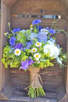 a bouquet of blue and white flowers in a wooden crate