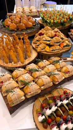 a table topped with lots of different types of food on trays next to each other