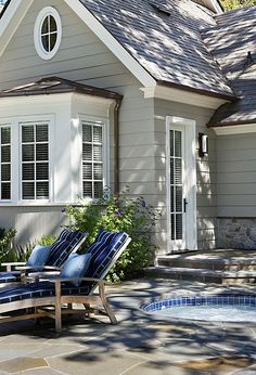 two lawn chairs sitting in front of a house with a hot tub next to it