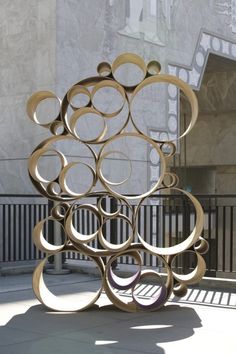 a sculpture is sitting on the sidewalk in front of a building with many circular shapes