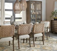 the dining room table is set with beige chairs and wicker baskets hanging from the ceiling