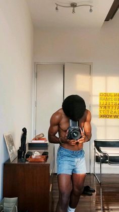 a shirtless man taking a selfie with his camera in front of the mirror