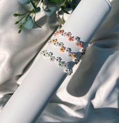 three bracelets on top of each other with flowers in the background and white satin