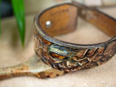 an old wooden bracelet sitting on top of a table next to a plant in a vase