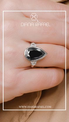 a woman's hand wearing a ring with an oval black stone in the center