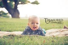 a baby laying on top of a blanket in the grass with his mouth wide open