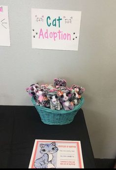 a basket filled with lots of stuffed animals next to a sign that says cat adoption