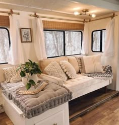 a living room with couches and pillows on the floor in front of two windows