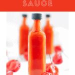 an orange liquid bottle with some cherries around it and the words sauce written in red