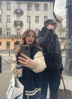 a woman taking a selfie with her cell phone in front of an old building