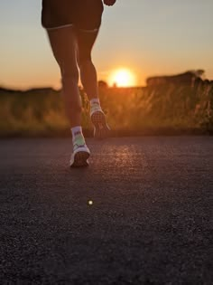 a person running down the road at sunset with their feet in the air and one foot on the ground