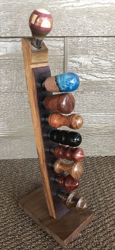 a wooden stand with several different colored vases on it's top and bottom