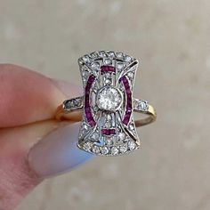 a woman's hand holding an antique diamond and ruby ring