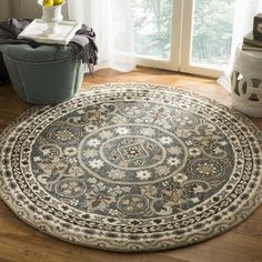 a large round rug with an intricate design on the floor in front of a window