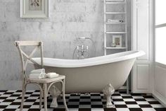 a white bath tub sitting next to a chair on top of a black and white checkered floor