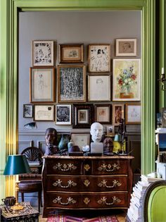 a room filled with lots of framed pictures on the wall and furniture in front of it