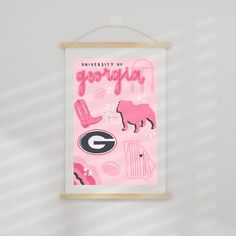 a pink poster hanging on a wall with the words university of georgia written in cursive writing