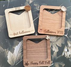 three personalized wooden photo frames sitting on top of a leaf covered table with autumn leaves