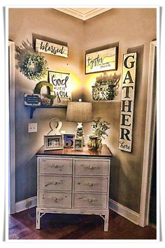 a white dresser sitting in a living room next to a wall with pictures on it