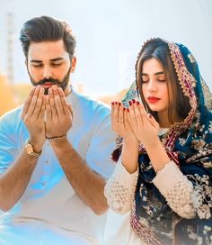 a man and woman standing next to each other with their hands together