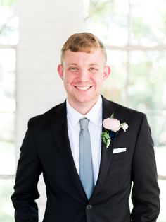 a man in a suit and tie smiling at the camera with his hands in his pockets