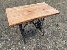 an old sewing machine table is sitting on the ground in front of some grass and trees