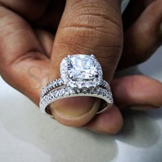 a close up of a person's hand holding an engagement ring and wedding band