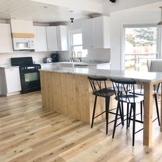 a kitchen with white cabinets and an island in the middle, surrounded by bar stools