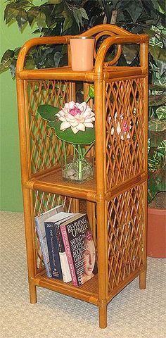 a wooden shelf with books and flowers on it in front of a potted plant