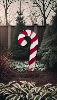 a large candy cane sitting in the middle of a garden