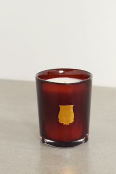 a red glass candle sitting on top of a table