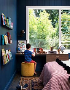 a young boy sitting on a stool in his bedroom