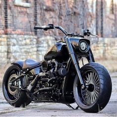 a black motorcycle parked in front of a brick wall