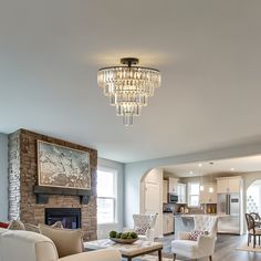 a living room filled with furniture and a chandelier hanging from the ceiling over a fire place