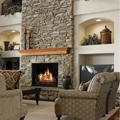 a living room filled with furniture and a fire place in the middle of a stone fireplace