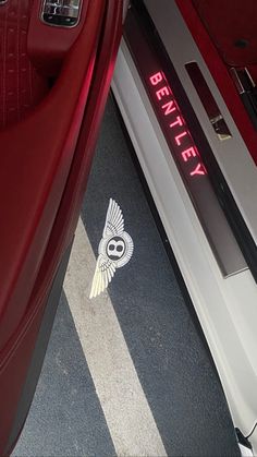 a red car with the word bentley on it's side door and an owl sticker