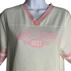 a white shirt with pink trims on the chest and sleeves that says john deere