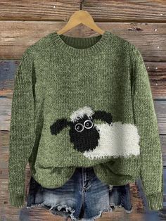 a green sweater with a black sheep on the front and white sheep on the back