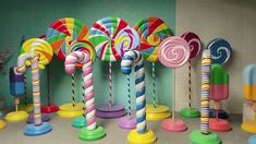 colorful candy canes are lined up on pedestals in front of a green wall