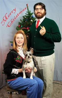 a man and woman posing for a photo with a dog in front of a christmas tree