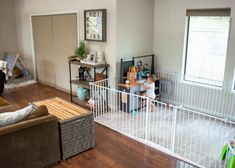 a young child standing in the living room next to a baby gate that is open