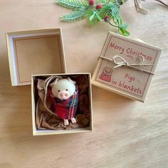 a small toy pig in a box on a table next to a christmas ornament