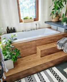 a bath tub sitting next to a window with potted plants on the counter top