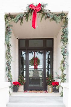 the front door is decorated for christmas with greenery and wreaths