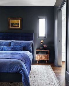 a bedroom with dark walls and blue bedding